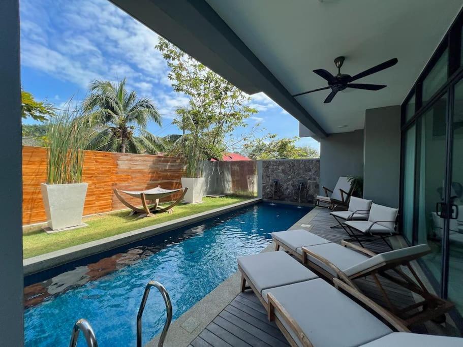 a swimming pool with chairs and a ceiling fan at La Mer Luxury Private Pool Villa in Pantai Cenang
