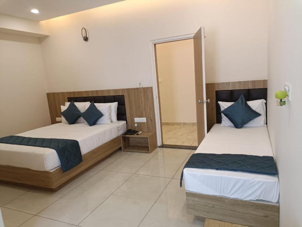 1 dormitorio con 2 camas y espejo en SIGNATURE INN, en Chikmagalur