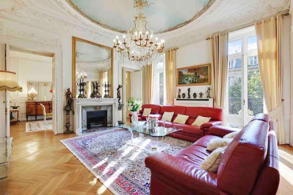 Champs Élysées : Appartement 200 m2 avec balcon في باريس: غرفة معيشة بها أريكة حمراء وثريا