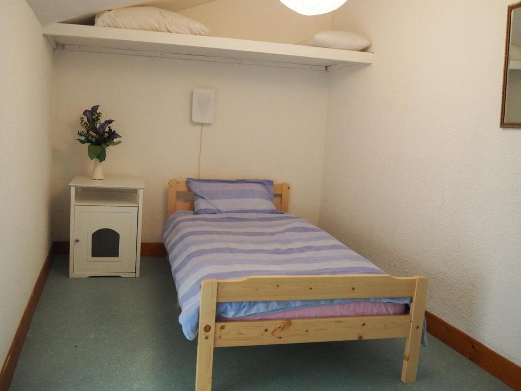 a small bedroom with a bed and a night stand at Gencay La maison blanche in Gençay