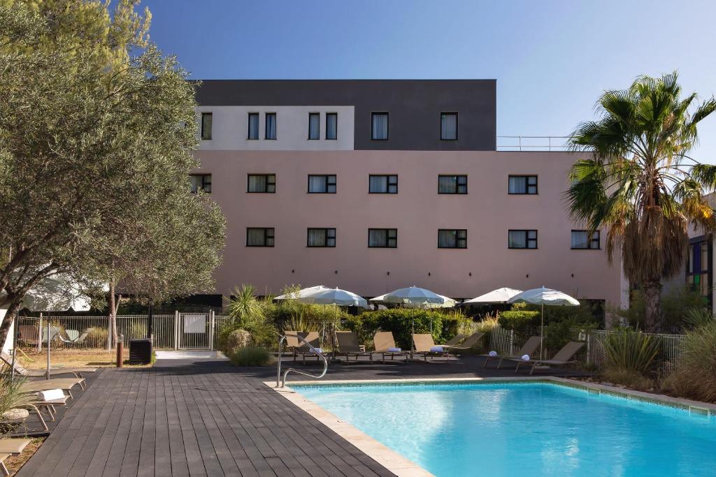un hotel con piscina di fronte a un edificio di Holiday Inn - Marseille Airport, an IHG Hotel a Vitrolles