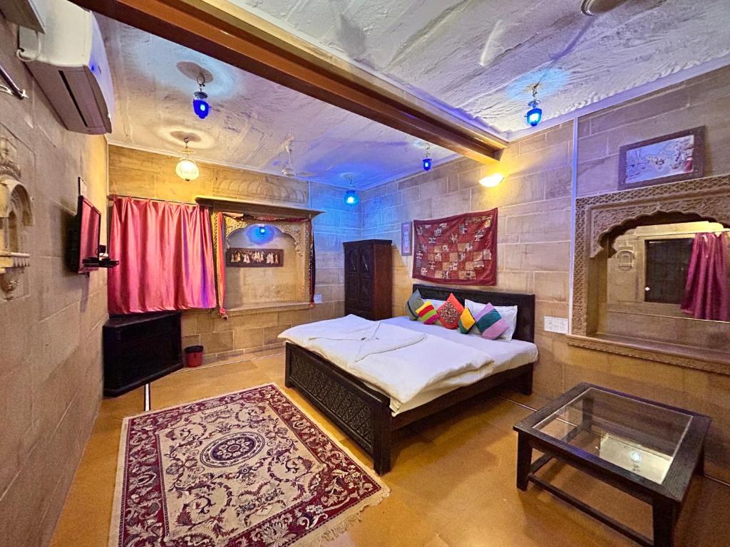 a bedroom with a bed and a table in a room at Hotel Pol Haveli Jaisalmer in Jaisalmer