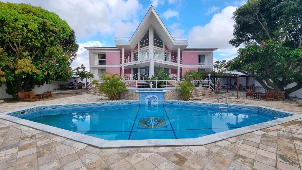ein rosafarbenes Haus mit einem Pool davor in der Unterkunft Casa da Barbie na praia de Carapibus PB in Conde