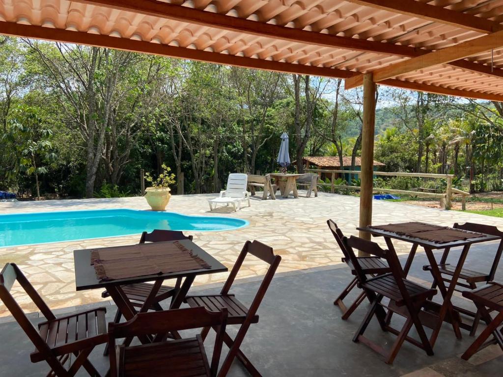 un patio con mesas y sillas junto a una piscina en Pousada Casa Ferreira, en Pirenópolis