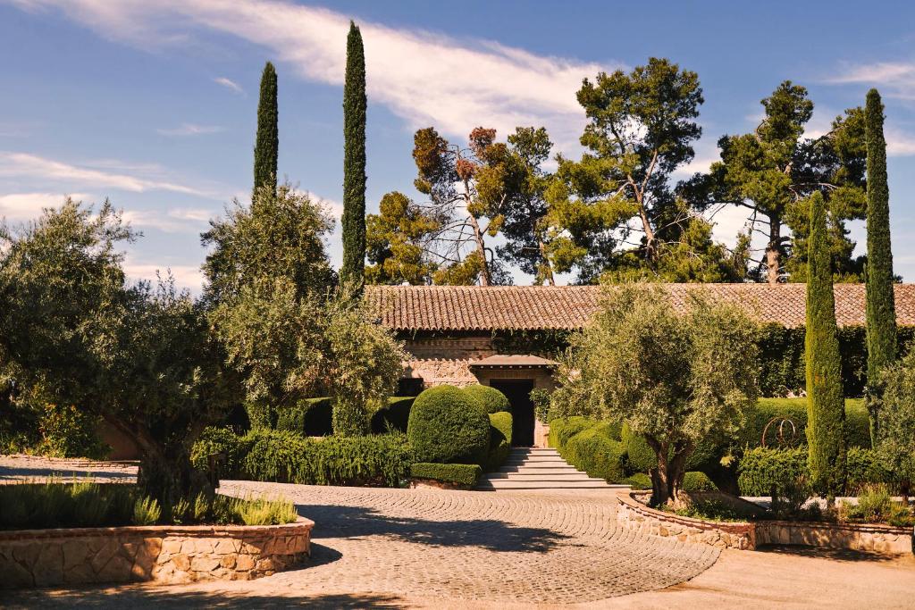 um jardim com árvores e arbustos e um edifício em Hotel Boutique Cigarral de las Mercedes em Toledo