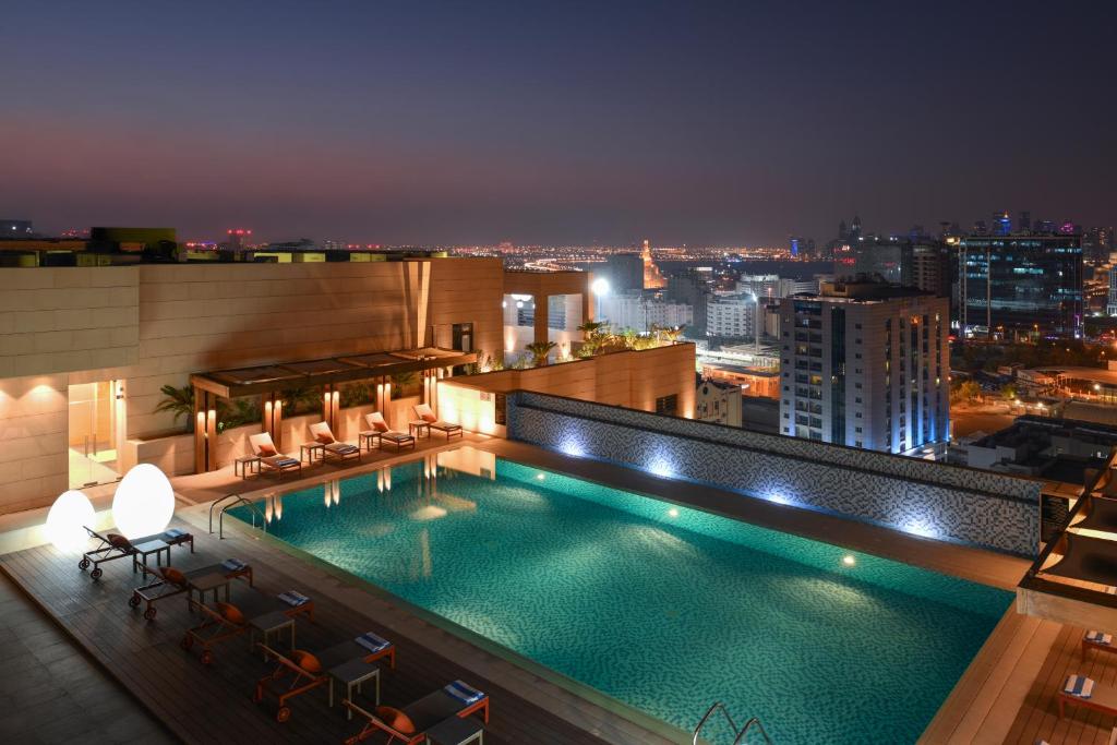 a swimming pool on top of a building at night at Le Mirage Downtown in Doha
