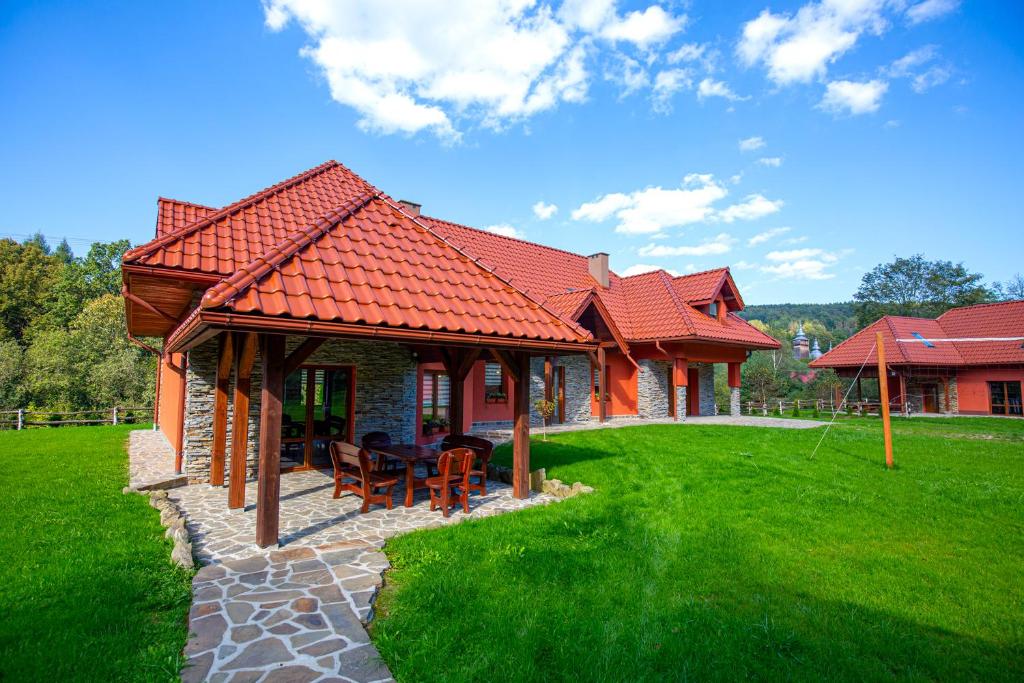 una casa con techo rojo en un césped verde en Siedlisko Leszczyny en Kunkowa