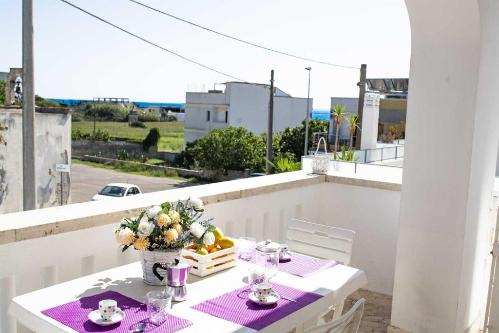 een witte tafel met een vaas met bloemen op een balkon bij Appartamenti in Via Schipa Pescoluse in Marina di Pescoluse