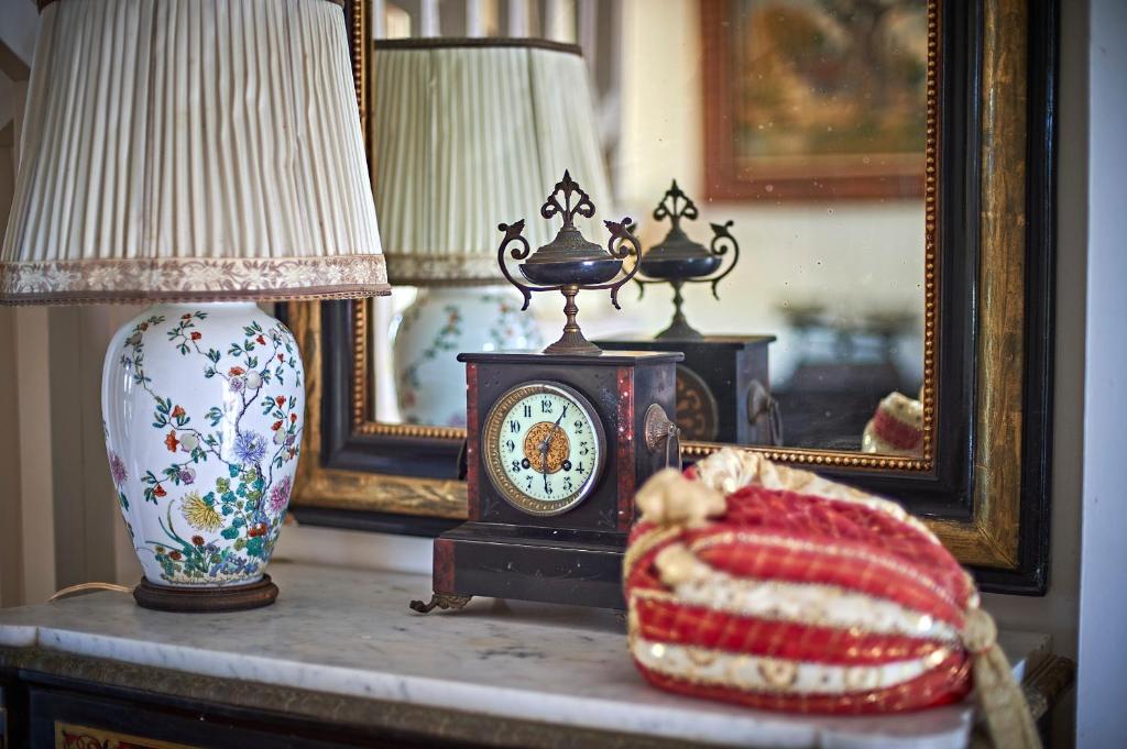a table with a clock and a lamp and a vase at VILLA MERCEDES 300 m de la plage in La Londe-les-Maures