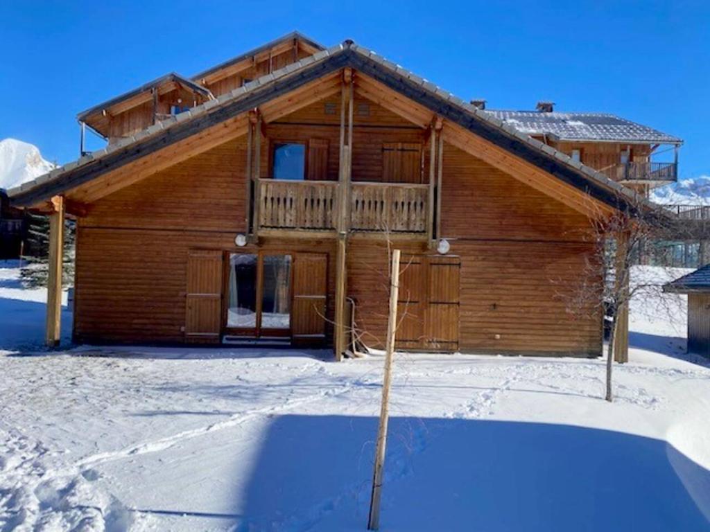 a log cabin in the snow with a balcony at Chalet de 3 chambres a Le Devoluy a 200 m des pistes avec piscine partagee sauna et terrasse in Le Dévoluy