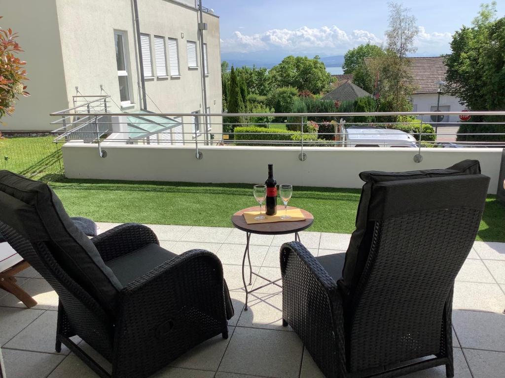 - une terrasse avec 2 chaises et une table avec une bouteille de vin dans l'établissement Bellevue, à Immenstaad am Bodensee