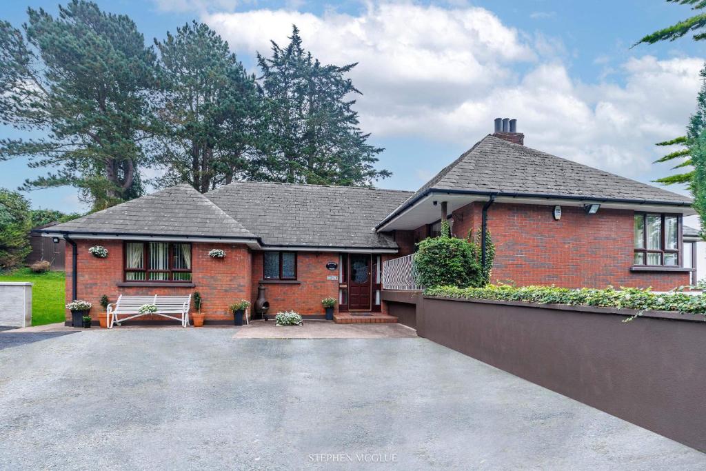 a red brick house with a bench in the driveway at Dunleath House in Downpatrick