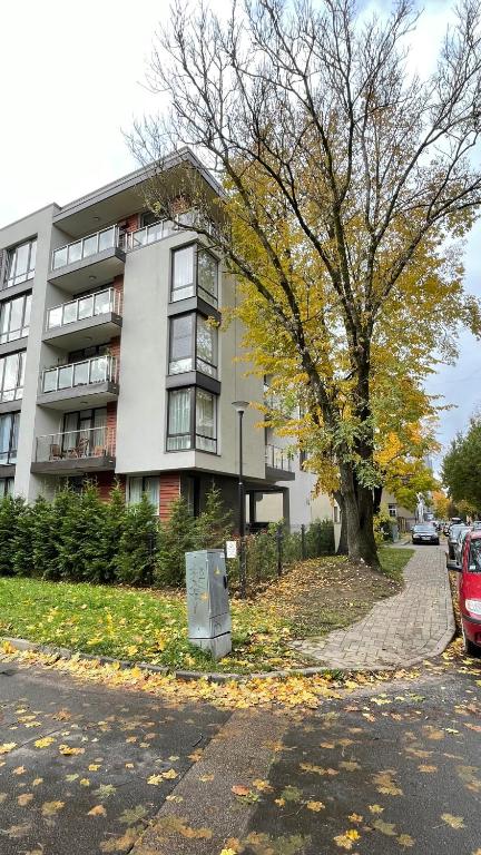 ein Apartmenthaus mit einem Baum davor in der Unterkunft Hugo apartment & parking in Riga