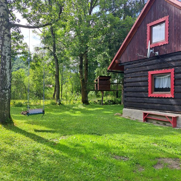 a log cabin with a red roof and a swing at Drevenica Emma in Oravská Polhora