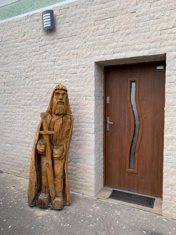 a wooden statue sitting in front of a building at U lesního muže in Střelice