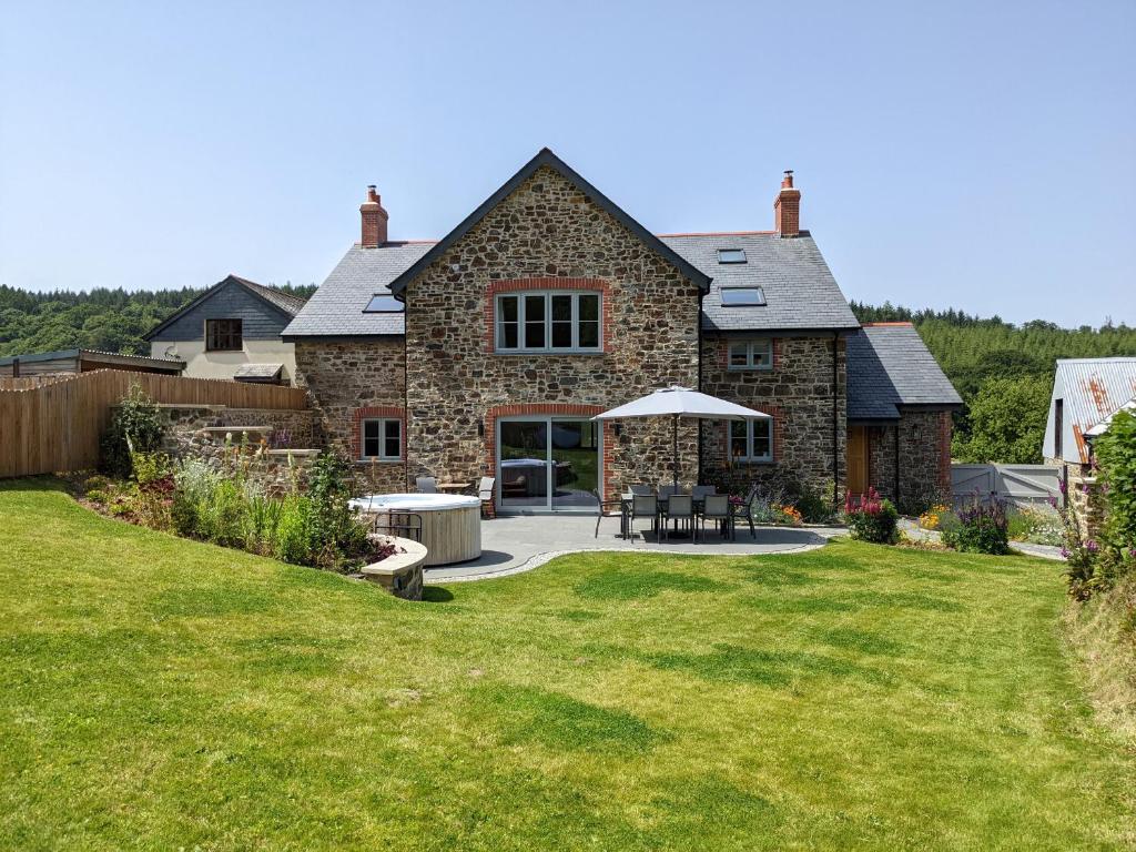 a stone house with a patio and a lawn at Knowle House in Okehampton