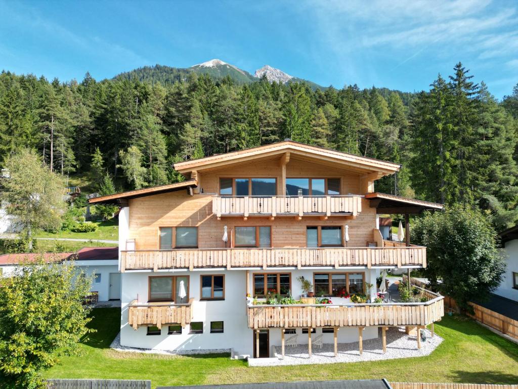 a house with a deck and mountains in the background at MY APARTMENT krinzwald in Seefeld in Tirol