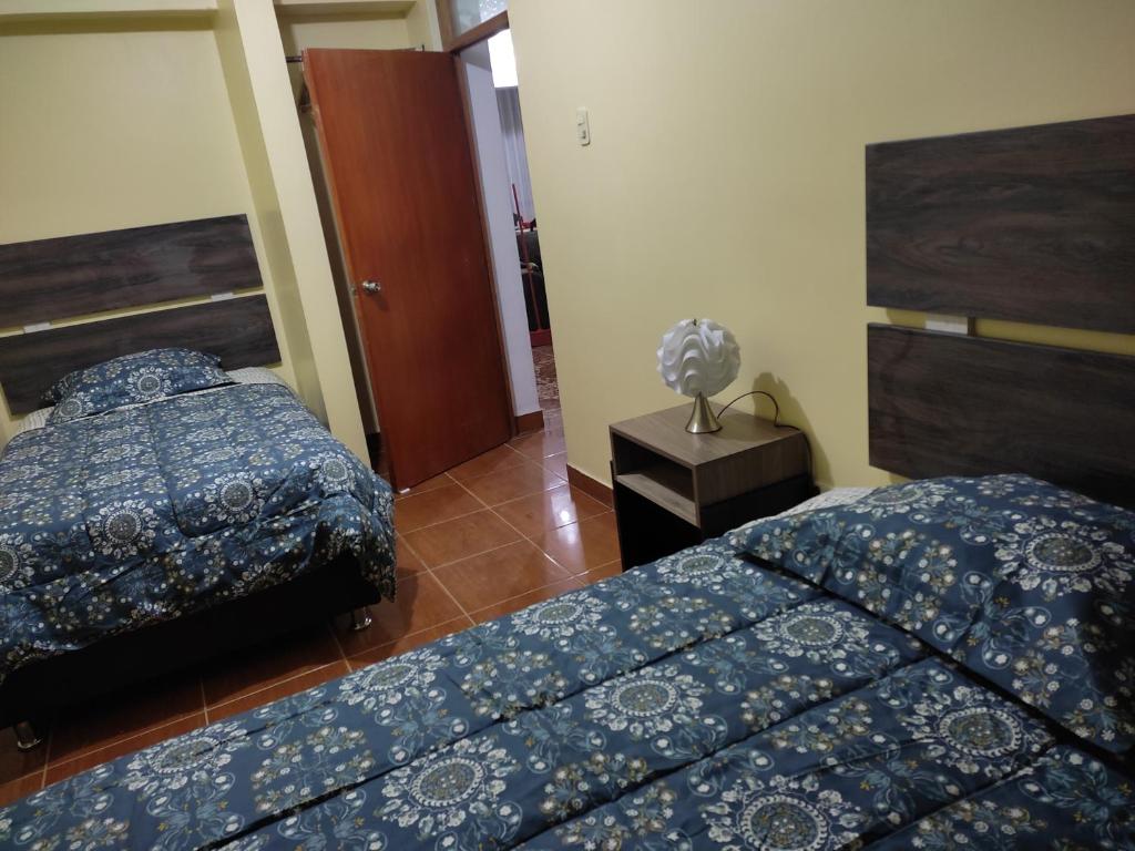 a bedroom with two beds and a lamp on a table at I - Apartamento QOSQO in Cusco