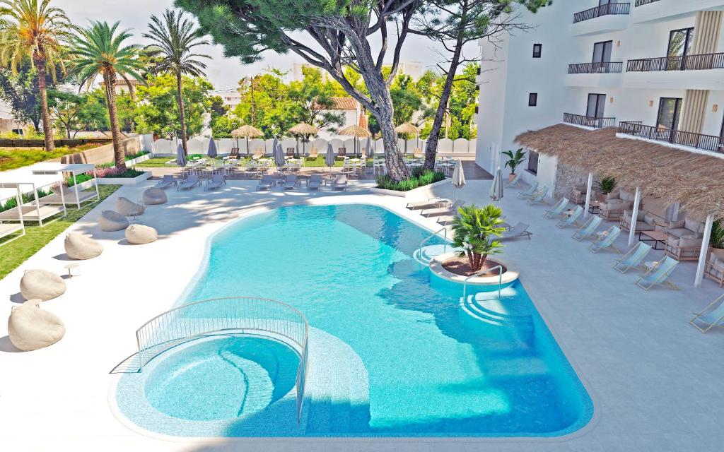 una piscina con sillas y un edificio en Copaiba by Honne Hotels, en Playa de Palma
