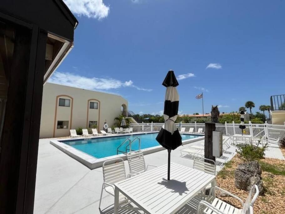 a pool with chairs and an umbrella in front of a house at NEW condo! Just 15 min to Ft Myers and Sanibel beach! Great Location!! in Fort Myers