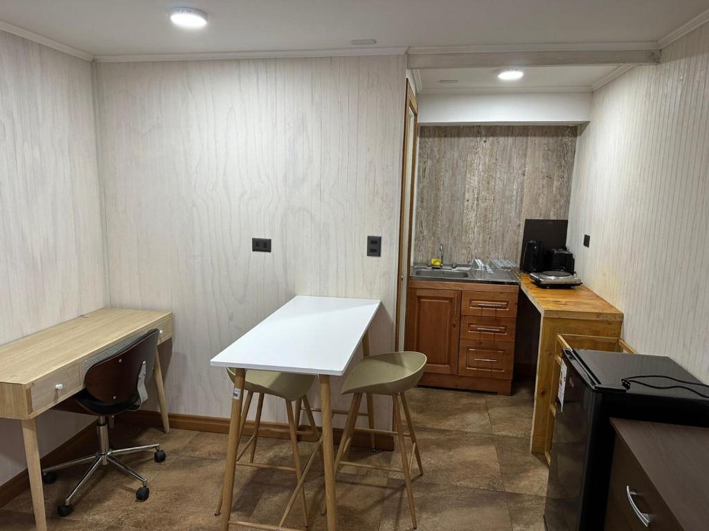 Il comprend une petite cuisine avec un bureau, une table et des chaises. dans l'établissement Hospedaje CYR, à Temuco