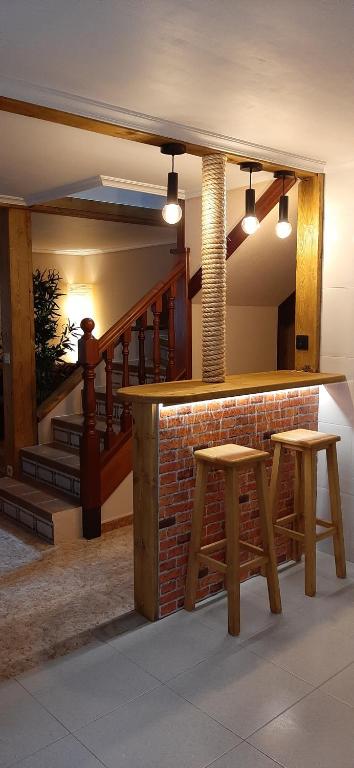a bar with two stools in a room with a staircase at La Casa del Rio. in La Serna