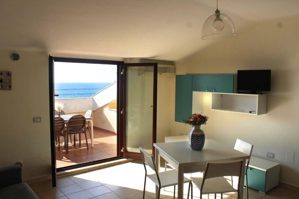 una cucina e una sala da pranzo con tavolo e vista sull'oceano di Il Borgo della Marinella Case Vacanze ad Amantea