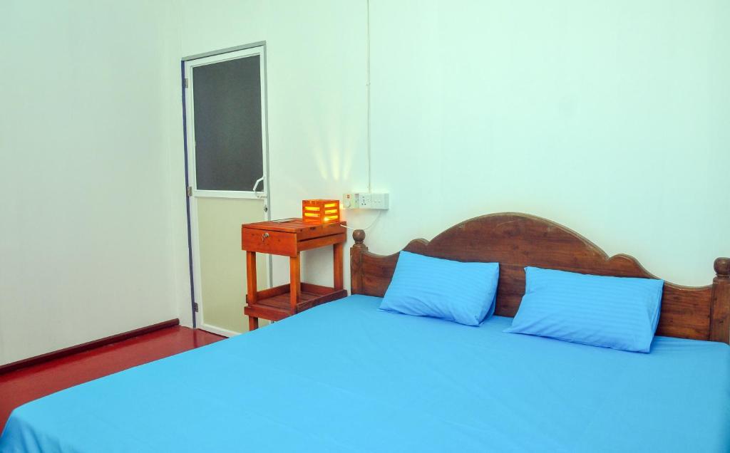 a bedroom with a bed with blue pillows and a window at Airport Tourist Resort in Katunayake