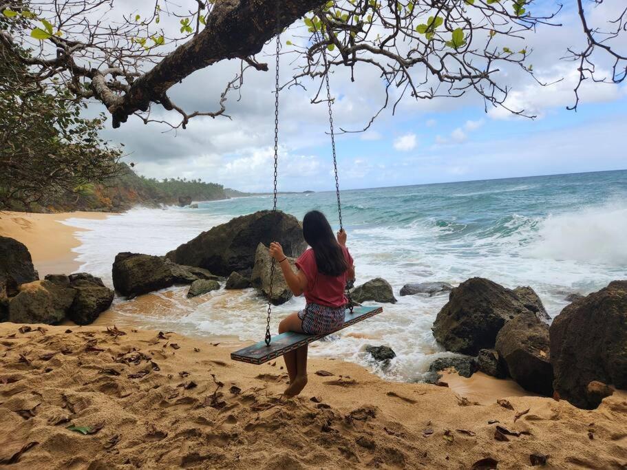 une femme assise sur une balançoire sur la plage dans l'établissement Family & Friends - Beach, BBQ, Private Pool & Pet, à Vega Baja