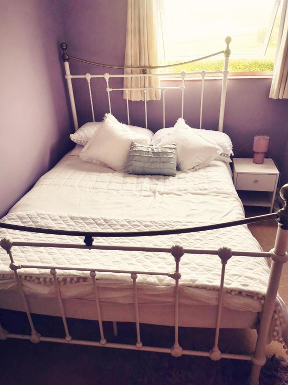 a bed with white pillows and a window at Newbrea Room 2 in Axminster