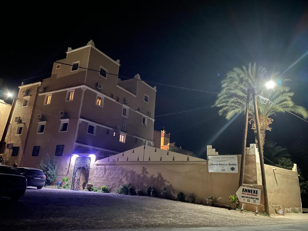 un gran edificio por la noche con una palmera en Riad Les Roches Todra, en Tinerhir