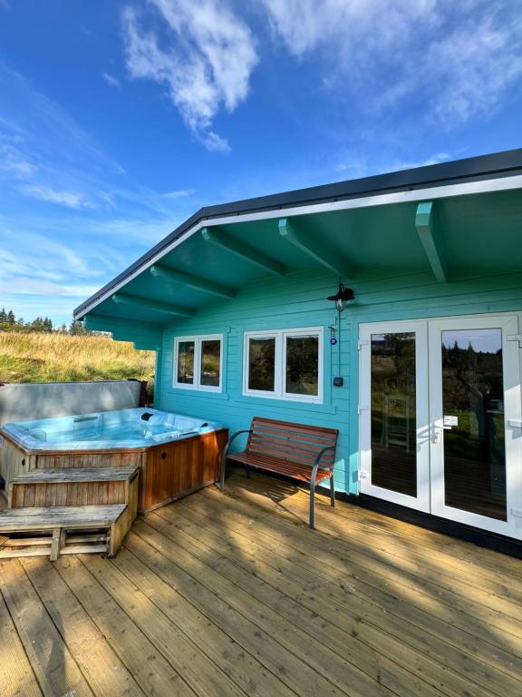 a blue house with a hot tub on a deck at Glenariff Forest Pine Cabin in Glenariff