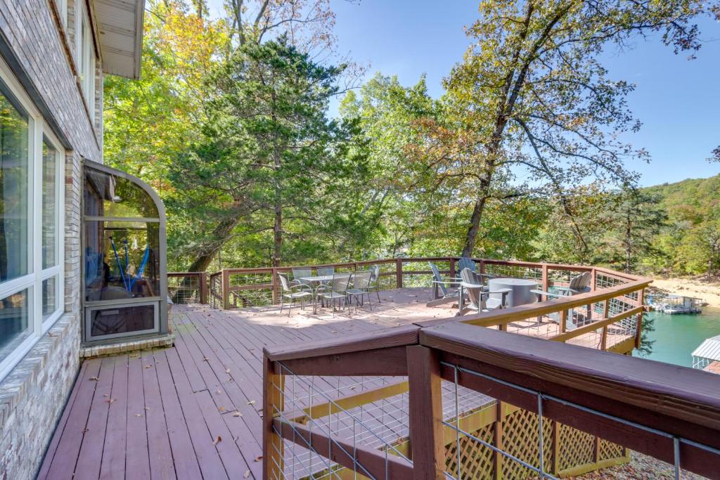 een houten terras met tafels en stoelen op een huis bij Waterfront Eureka Springs Vacation Rental with Deck in Eureka Springs