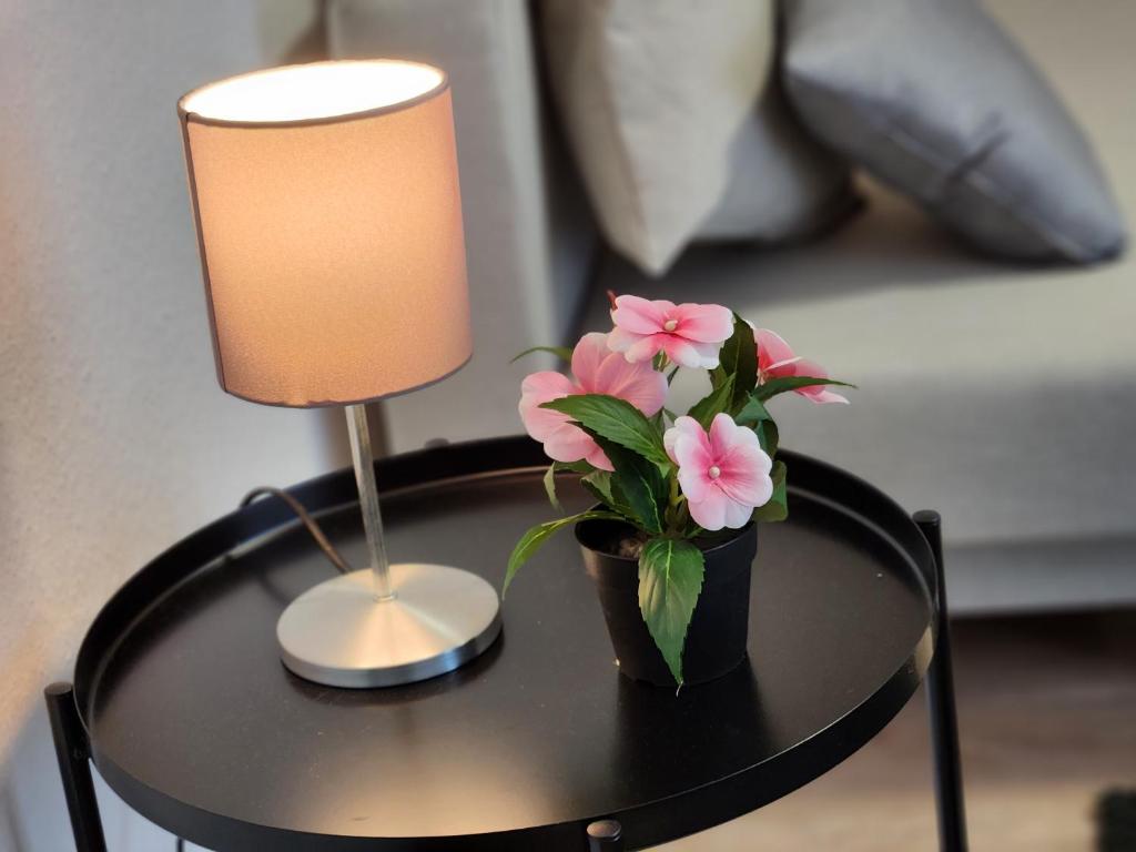 een tafel met een lamp en een vaas met bloemen erop bij Nd Hotels & Apartments Oberstrasse Mülheim in Mülheim an der Ruhr