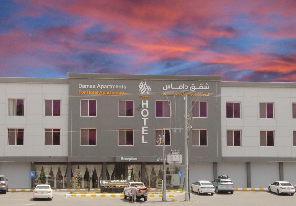 un gran edificio con coches estacionados frente a él en داماس للأجنحة الفندقية Damas Hotel Suites, en Al Maraghah