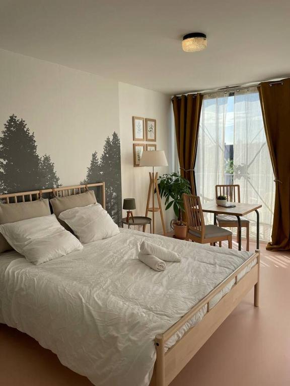 ein Schlafzimmer mit einem großen weißen Bett und einem Tisch in der Unterkunft Charmant Studio avec parking - Confort Moderne in Bourges