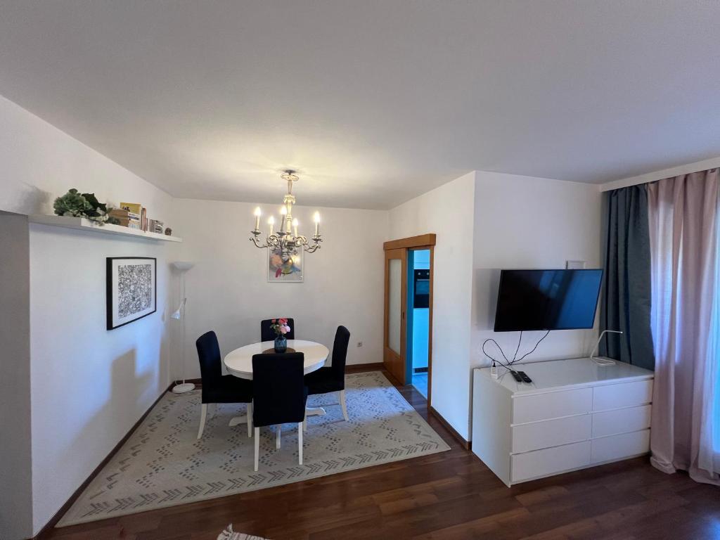 a living room with a table and chairs and a television at Stylish Youthful Condo in the Heart of Mödling, Fiatalos Boldog Otthon Mödling Szivében in Mödling