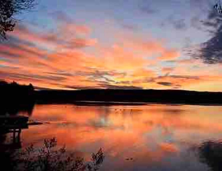 una pintura de una puesta de sol sobre un cuerpo de agua en Bienvenue au paradis!, en Dunham