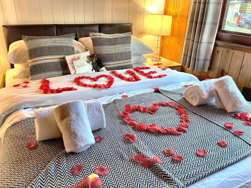 a bed with red roses and a heart made out of towels at Snowdrop 13-Hot Tub-Woodlandlodges-Carmarthenshire in Carmarthen