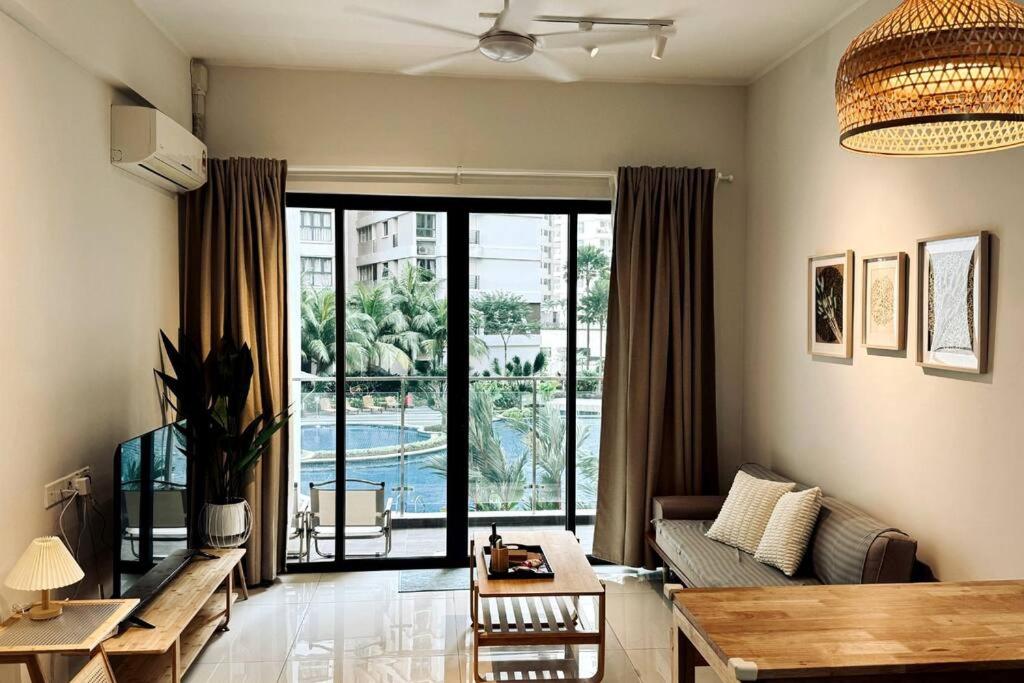 - un salon avec un canapé et une grande fenêtre dans l'établissement Poolside Haven: 2BR Garden Oasis, à Johor Bahru