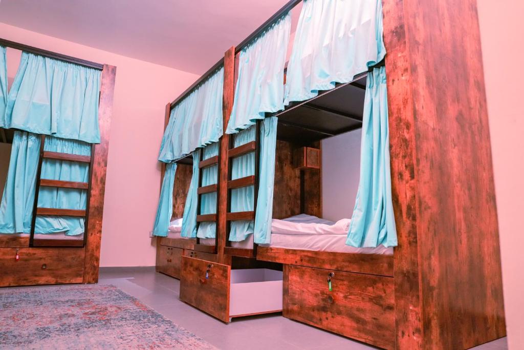 2 literas en una habitación rosa con cortinas azules en The Villa Hostel Abu Dhabi, en Abu Dabi