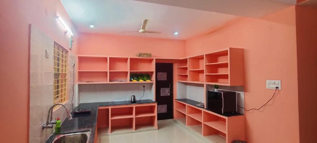 a kitchen with orange walls and a sink and a microwave at RUSHITHA HOME STAY-AC Rooms-FREE WIFI-FLAT TV- KITCHEN-DOOR SERVICE-NEAR TO ALIPIRI in Tirupati