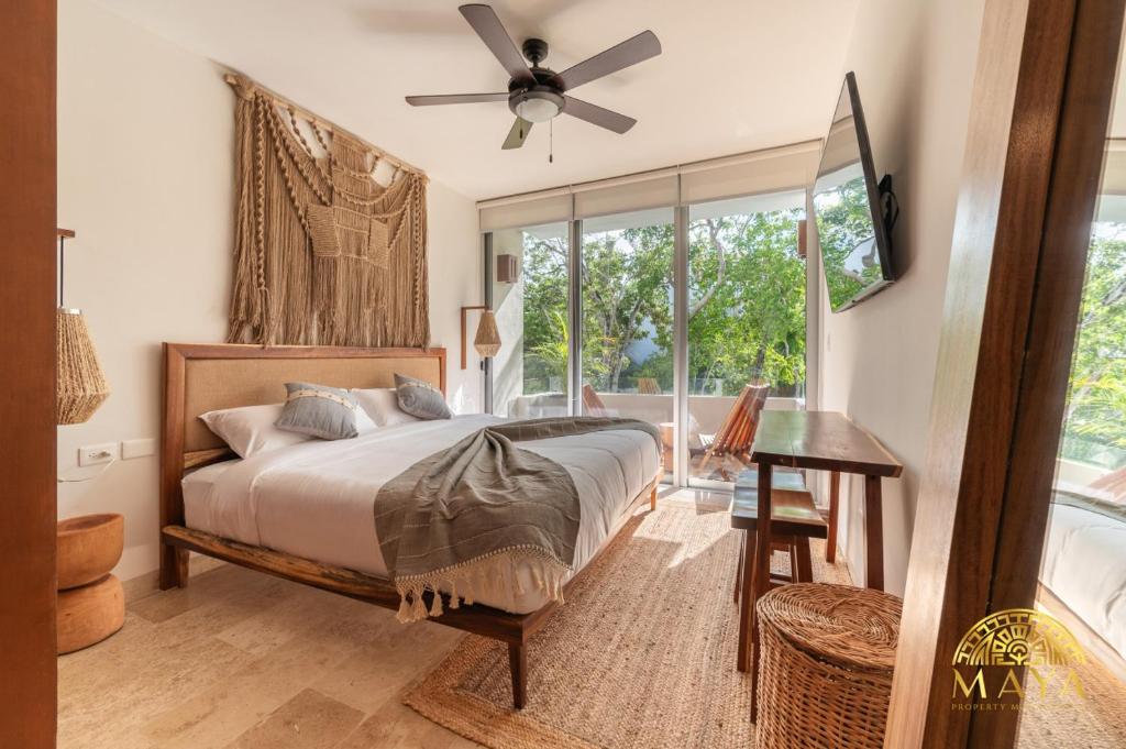 Schlafzimmer mit einem Bett, einem Deckenventilator und einem Fenster in der Unterkunft NHOA 209A Lux 2BR Condo Pool View in Aldea Zama in Tulum