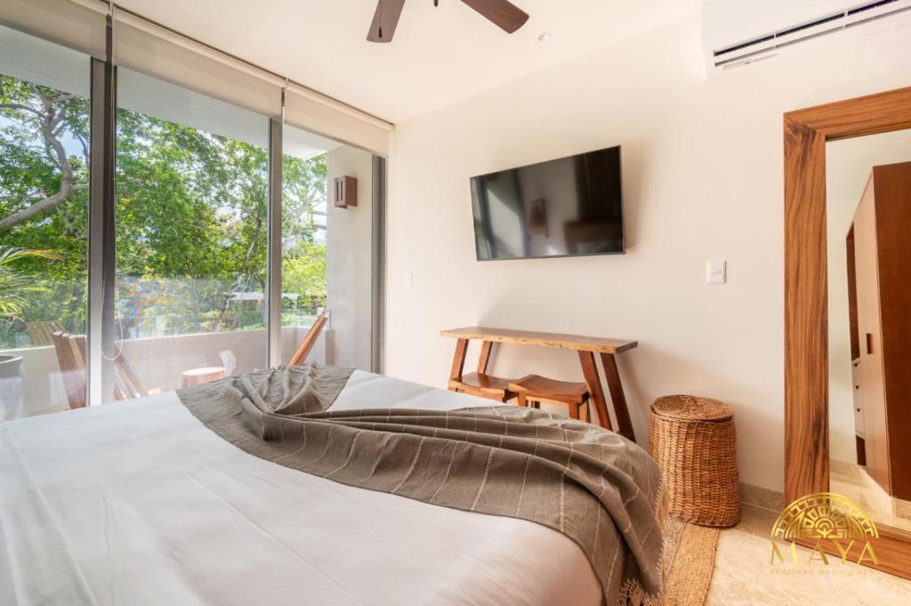 ein Schlafzimmer mit einem Bett und einem großen Fenster in der Unterkunft NHOA 209B Lux 1BR Condo Pool View in Aldea Zama in Tulum