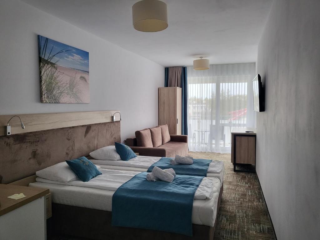 Habitación de hotel con 2 camas y sofá en Apartament Suzi en Grzybowo
