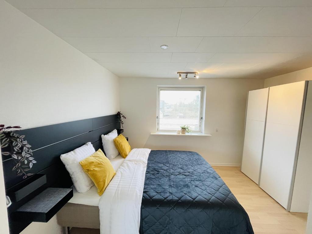 a bedroom with a bed with yellow pillows and a window at aday - Modern 3 bedrooms apartment in Svenstrup in Svenstrup