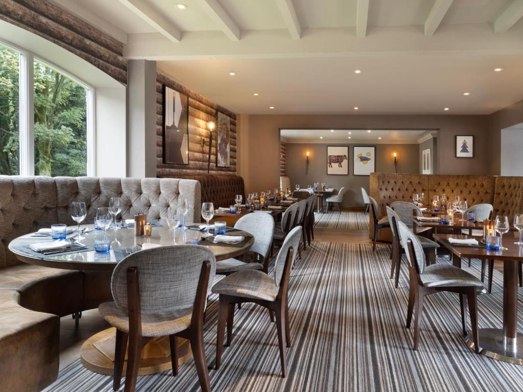 ein Restaurant mit Tischen und Stühlen und einer Couch in der Unterkunft Delta Hotels by Marriott Worsley Park Country Club in Worsley