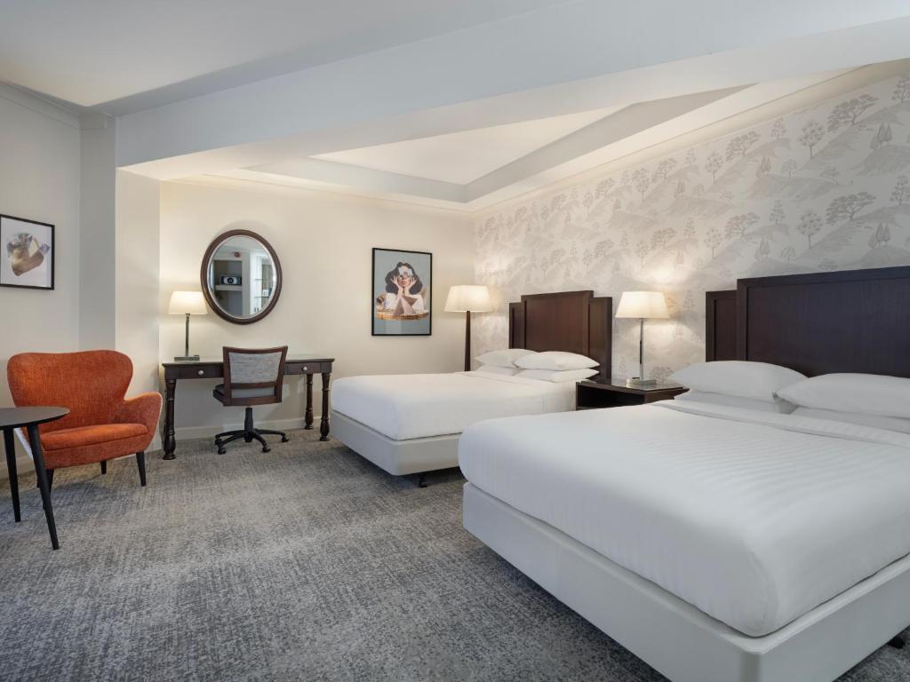 ein Hotelzimmer mit zwei Betten und einem Schreibtisch in der Unterkunft Delta Hotels by Marriott Worsley Park Country Club in Worsley