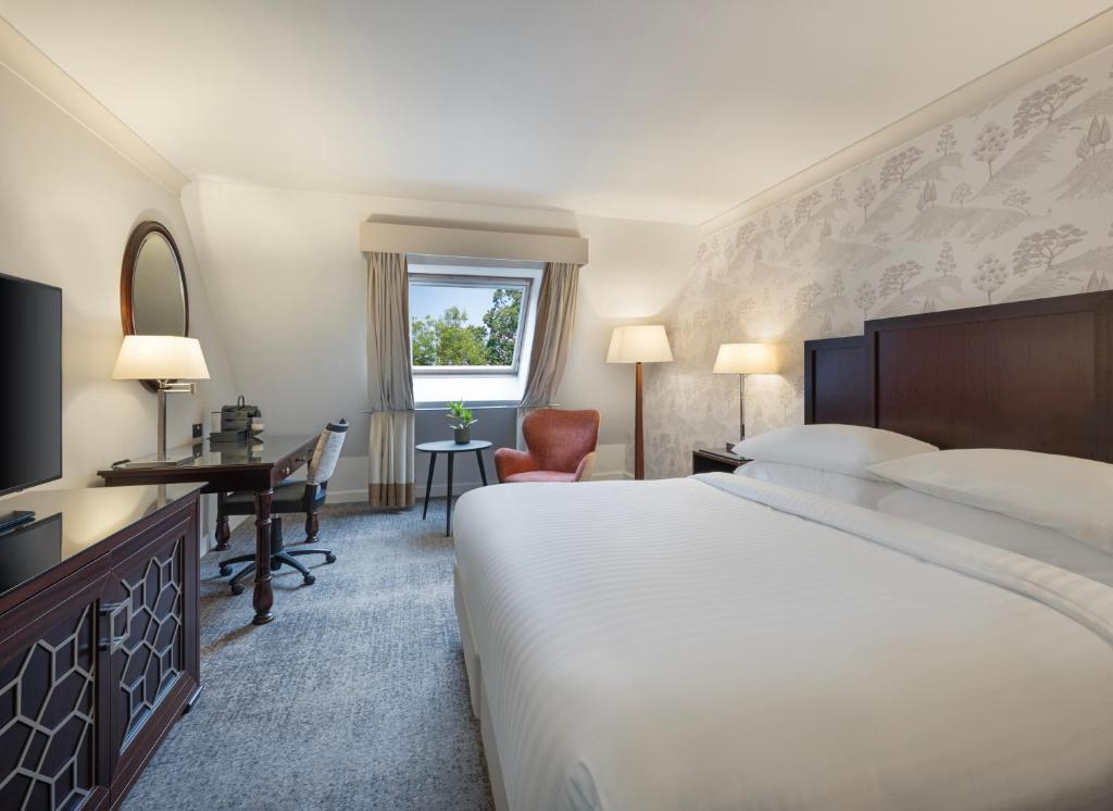 ein Hotelzimmer mit einem großen Bett und einem Schreibtisch in der Unterkunft Delta Hotels by Marriott Worsley Park Country Club in Worsley