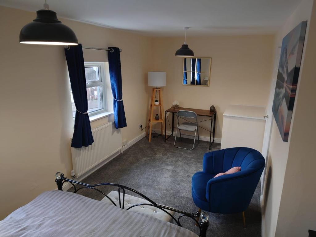 a bedroom with a blue chair and a bed at Family friendly home near Alton Towers in Stoke on Trent